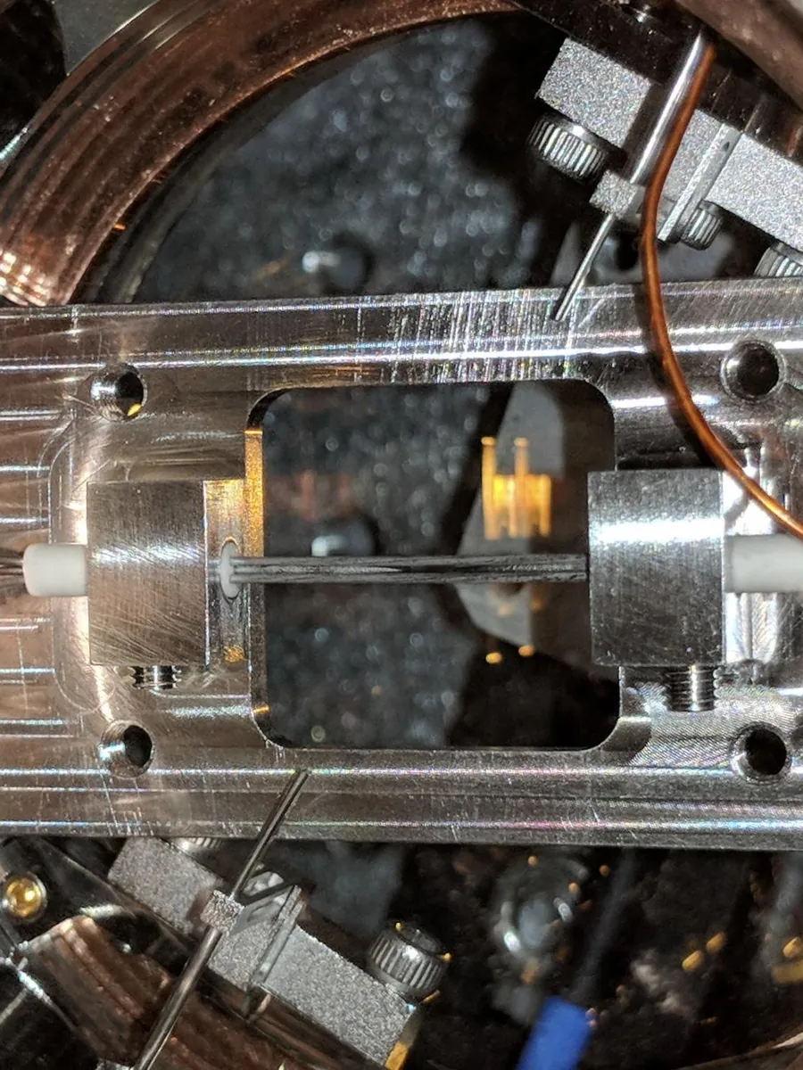 A linear Paul trap inside a vacuum chamber: polished metal electrodes around a small opening.